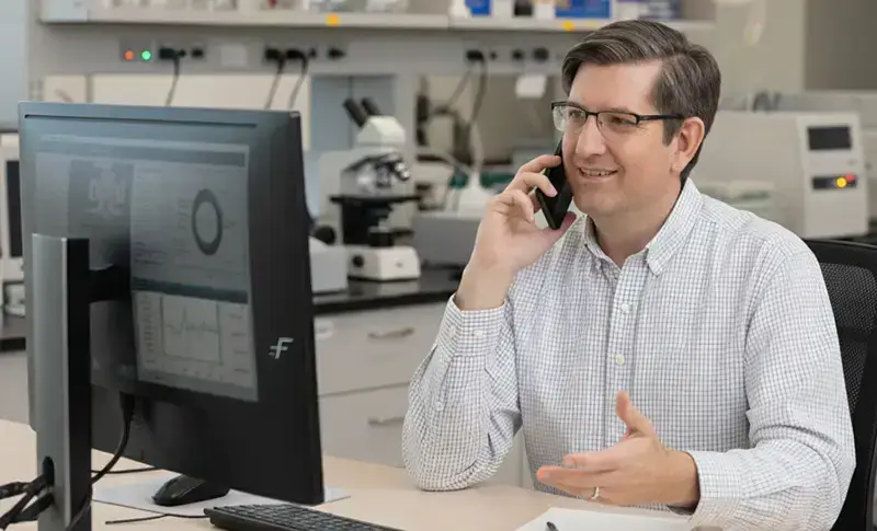 Mann im weißen Hemd am Telefon während der Kundenbetreuung.